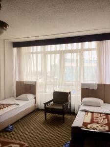 a room with two beds and a chair and a window at KAYAPALI OTEL in Bursa