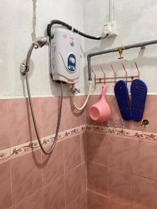 a shower in a bathroom with a blow dryer at Teratak Tiga Homestay Padang Besar in Kaki Bukit