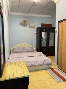 een slaapkamer met een bed en een tafel. bij Teratak Tiga Homestay Padang Besar in Kaki Bukit