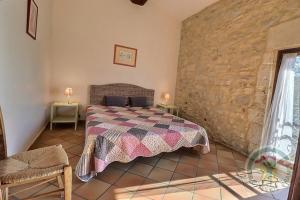 een slaapkamer met een bed en een stenen muur bij Mas des Esclots in Nîmes