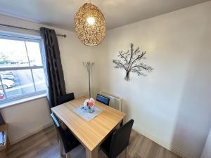 a dining room with a table and a chandelier at Meadowside Apartment - Part of the The Bay Filey Holiday Village with pool, gym and direct beach access, pub, restaurant, tennis and meadows walks in Filey
