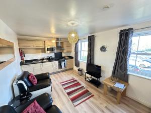 a living room with a couch and a kitchen at Meadowside Apartment in Filey