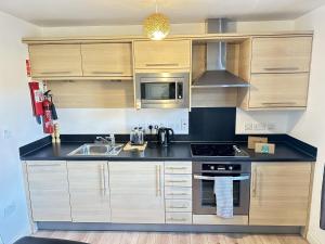 a kitchen with a sink and a stove top oven at Meadowside Apartment - Part of the The Bay Filey Holiday Village with pool, gym and direct beach access, pub, restaurant, tennis and meadows walks in Filey