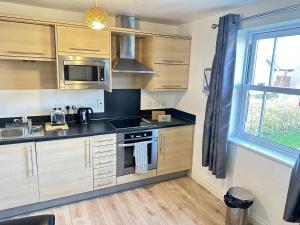 a small kitchen with wooden cabinets and a window at Meadowside Apartment - Part of the The Bay Filey Holiday Village with pool, gym and direct beach access, pub, restaurant, tennis and meadows walks in Filey +34 photos