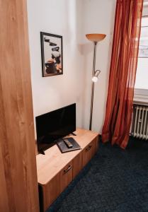 um quarto com uma secretária, uma televisão e um candeeiro em Hotel Haus Christel em Willingen