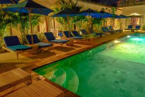 a swimming pool with blue chairs and umbrellas at Kura Kura Resort Gili Meno in Gili Meno