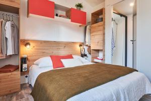 a bedroom with a large bed and red cabinets at Camping La Mignardière in Ballan-Miré