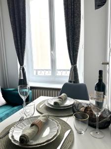 - une table à manger avec des assiettes et des verres à vin dans l'établissement 1587 - Cosy apartment in Paris Olympic Games 2024, à Paris