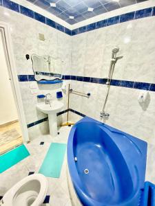 y baño con bañera azul y lavamanos. en ALEX HOMES - Stanley Cozy Apartments with Direct Sea View, en Alejandría