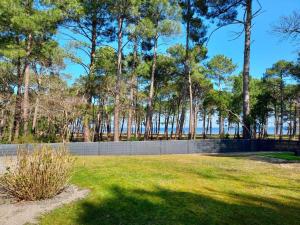 a park with a fence and trees and grass at Maison du Lac avec Lagon, Spa de Nage, Jacuzzi in Biscarrosse