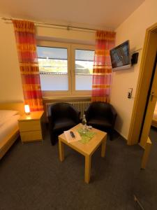 Hotel Haus Christel في فيلنغن: غرفة فندقية بسرير وطاولة وكراسي