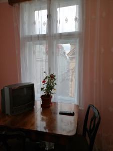 une télévision assise sur une table devant une fenêtre dans l'établissement La 2 pași de Biserica Neagră, à Braşov