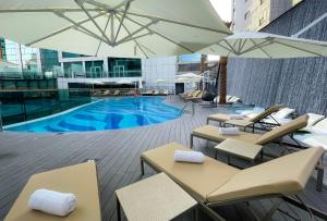 una piscina con mesas, sillas y sombrillas en Al Khoory Sky Garden Hotel en Dubái