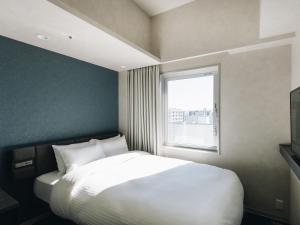 a bedroom with a white bed and a window at Prince Smart Inn Miyazaki in Miyazaki