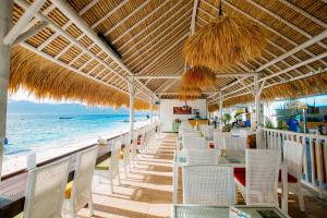 a beach restaurant with white chairs and a view of the ocean at Kura Kura Resort Gili Meno in Gili Meno