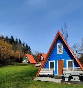 una casa azul con dos bancos en un campo en Kolorowe Wzgórze Zagórze, en Zagórze Śląskie