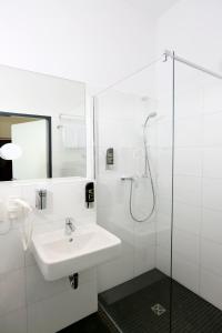 a white bathroom with a sink and a shower at H24 Hoteltow in Teltow