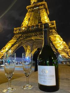 Uma garrafa de vinho e dois copos em frente à Torre Eiffel. em Rynek Pokoje Paris -Parking em Kielce