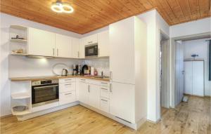 a kitchen with white cabinets and a wooden ceiling at Ferienhaus 41 Altefähr in Altefähr