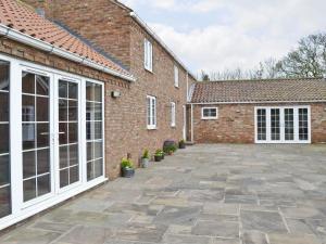 a brick building with a large patio in front of it at Bumblebee Cottage in Skipsea