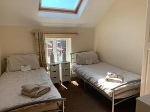 two beds in a small room with a window at Bumblebee Cottage in Skipsea