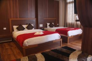 a bedroom with two beds with red sheets at East On Blue Hotel in Ilām