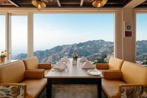 a dining room with a table and chairs and a large window at Tree of Life Highlands Mussoorie in Mussoorie