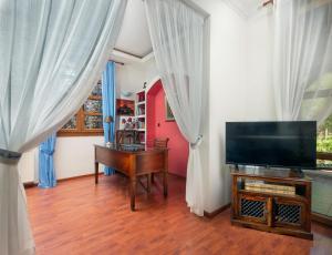 a living room with a television and a piano at Butterfly Garden Villa in Pastida
