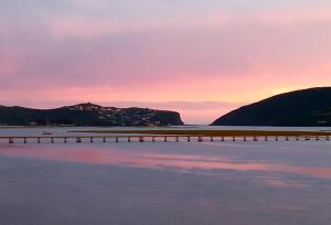 a sunset over a body of water with a pier at Phoenix Lodge and Waterside Accommodation in Knysna