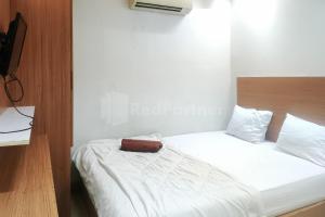 um quarto com uma cama branca e uma cabeceira em madeira em Tebet Glory House Mitra RedDoorz em Jakarta