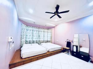 a bedroom with two beds and a ceiling fan at SingHome Holiday House in Mersing