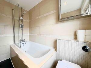 a white bathroom with a tub and a sink at Hyde Park- 1 Bed in London