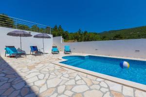 einen Pool mit Stühlen und Sonnenschirmen auf einer Terrasse in der Unterkunft Strandnahes Apartment mit Pool, Whirlpool in Klenovica