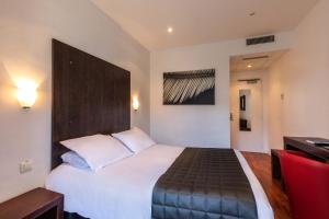 Habitación de hotel con cama grande y escritorio. en Hôtel Jeanne d'Arc, en Lourdes