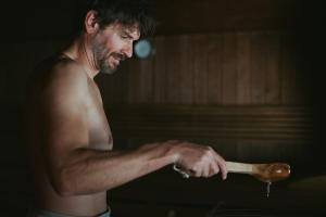 a shirtless man holding a wooden spoon at MANNI das Hotel in Mayrhofen