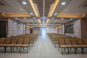 Habitación grande con filas de sillas y pasillo. en Hotel Amar Palace Ahmednagar en Ahmadnagar