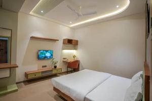 a bedroom with a bed and a desk and a tv at Hotel Amar Palace Ahmednagar in Ahmadnagar