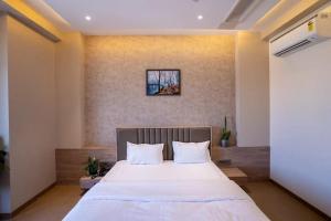 1 dormitorio con 1 cama grande con sábanas blancas en Hotel Amar Palace Ahmednagar en Ahmadnagar