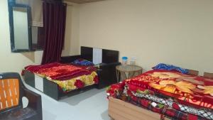 ein Schlafzimmer mit 2 Betten und einem Tisch darin in der Unterkunft Badrinath Jbk by Prithvi Yatra Hotel in Badrīnāth