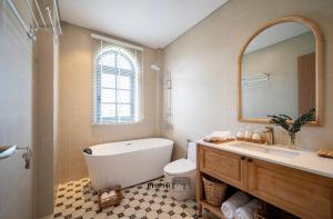a bathroom with a tub and a sink and a mirror at La Mer Villa in Bình Tú