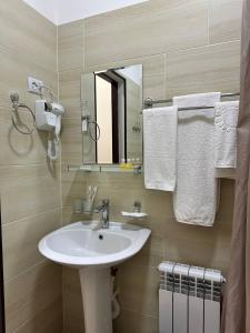 ein Badezimmer mit einem Waschbecken, einem Spiegel und Handtüchern in der Unterkunft HOTEL ARAL in Nukus