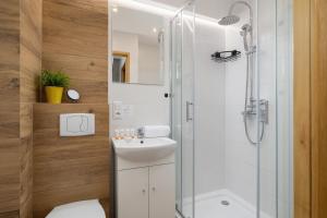 uma casa de banho branca com um chuveiro e um lavatório. em Katowice Centrum Nowoczesne Studio przy Spodku by Renters em Katowice