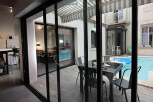 ein Wohnzimmer mit einem Tisch und einem Pool in der Unterkunft Villa Maurice avec piscine centre La Rochelle in La Rochelle