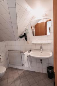 Baño blanco con lavabo y espejo en Hotel Haus Christel, en Willingen