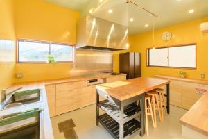 a kitchen with yellow walls and a wooden counter top at Ryokan -Suikoen- by Tranova in Yugawara