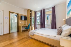 een slaapkamer met een bed, een bureau en een televisie bij Nur 140 Meter zum Strand mit Pool in Crikvenica