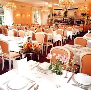 a dining room with white tables and chairs at Hôtel Jeanne d'Arc in Lourdes