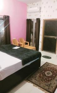 a bedroom with a bed and chairs and a window at Premshi Guest House in Ayodhya