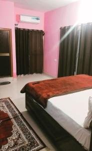 a bedroom with a large bed with pink walls at Premshi Guest House in Ayodhya