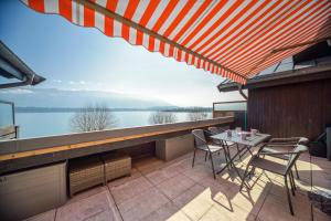 een balkon met een tafel en stoelen en uitzicht op het water bij Rooftop pieds dans l’eau, terrasse, parking sécu in Le Bourget-du-Lac